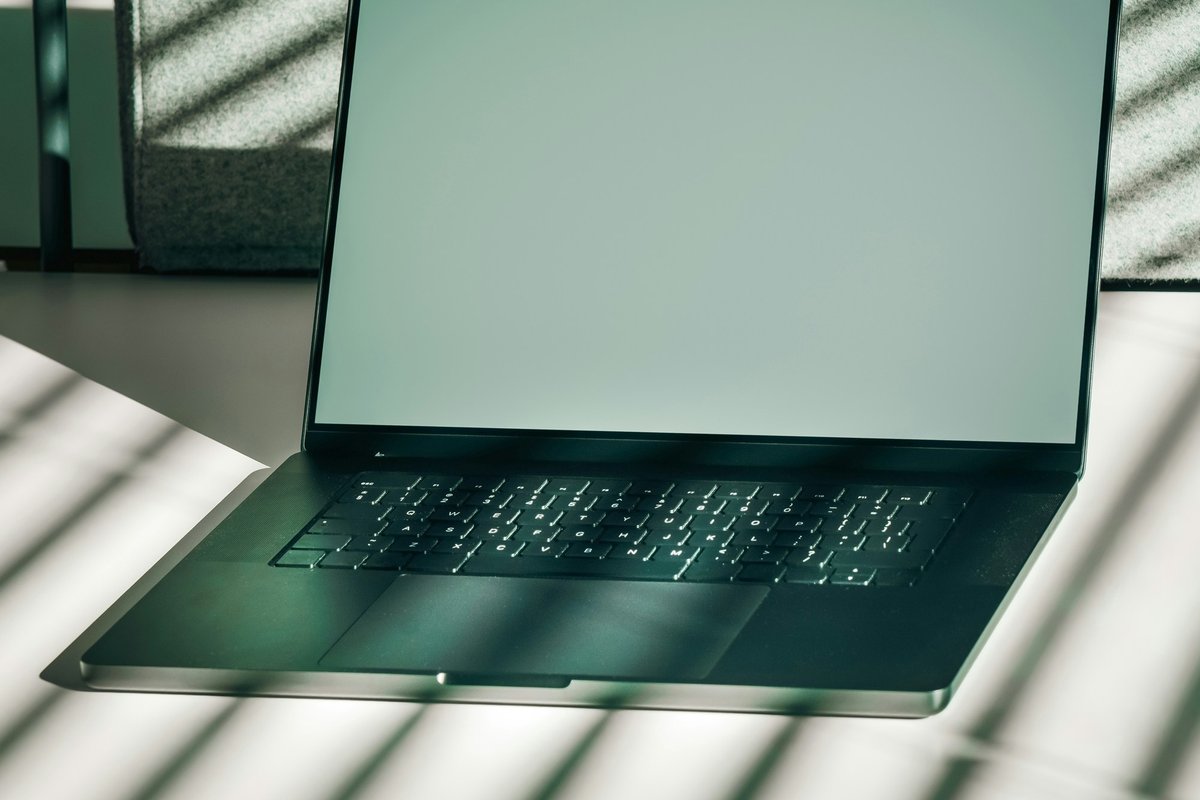 Open laptop with a blank screen on a clean desk in sunlight, suggesting a website build workspace