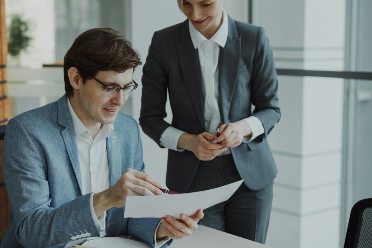 Two business professionals reviewing printed documents together in a modern office