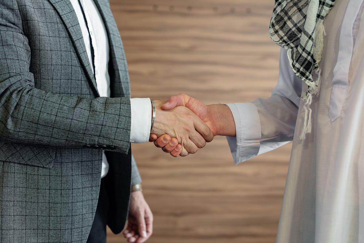 Two business professionals shaking hands in a warm partnership setting